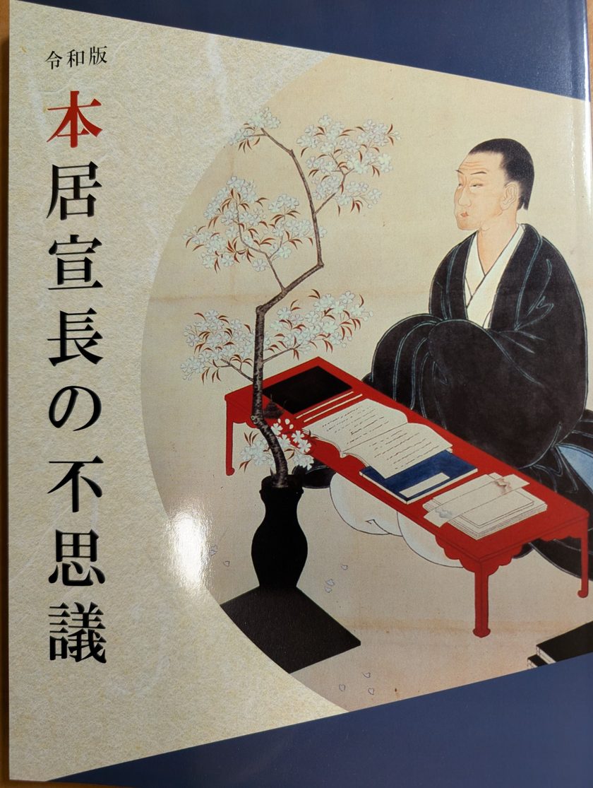 『令和版 本居宣長の不思議』表紙。本居宣長の肖像と桜、赤い文机